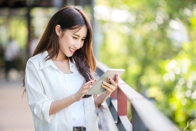 beautiful asian woman using tablet computer outdoor in the city to complete her own business. online business concept