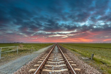 vanishing railroad on the horizon under a blue and red sky as a concept for future successfullness.