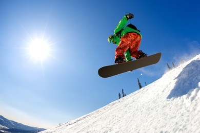 snowboarder jumping through air with deep blue sky in background