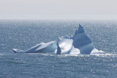 iceberg floating in silver ocean. sharp ice peak