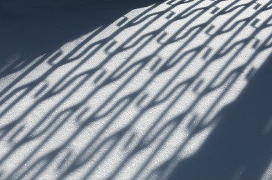 winter landscape. textural background. reflection of shadows on the snow with an artificial fence. shadow and light. landscape city