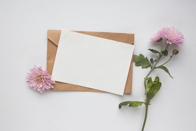 workspace. wedding invitation cards, craft envelopes, pink flowers and green leaves on white background. overhead view. flat lay, top view invitation card. ink pen, ink with copy space. mockup 