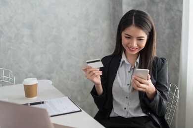 asian business girl in her workstation buying online with a credit card and smart phone. online shopping concept