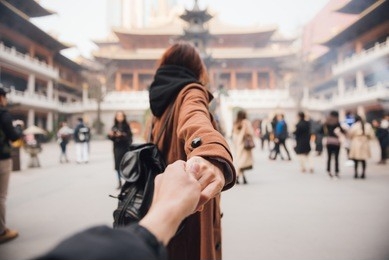 woman in jacket clothes leading man to the temple in shanghai. traveling together. follow me.