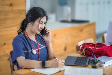 young woman doctor sitting with mobile and stethoscope.