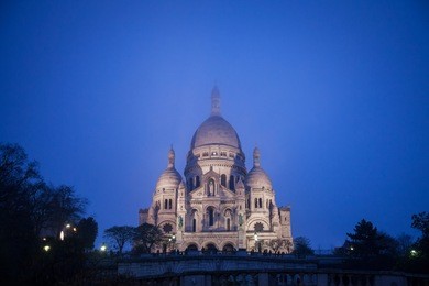 sacre coeur basilica in montmartre, paris, illuminated during a winter night. the basilica of the sacred heart of paris is a roman catholic church and minor basilica
