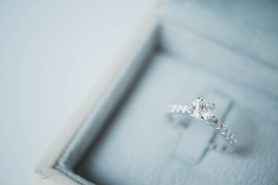 close up of elegant diamond ring in the gray box background. soft and selective focus.love and wedding concept.