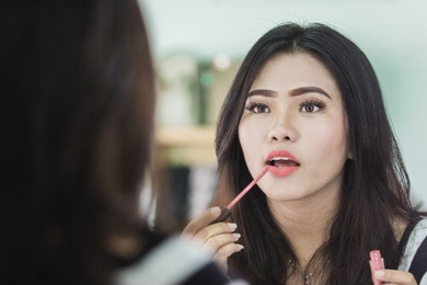 portrait of beautiful asian woman applying lipstick in make up room
