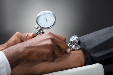close-up of male doctor measuring the blood pressure of patient against gray background