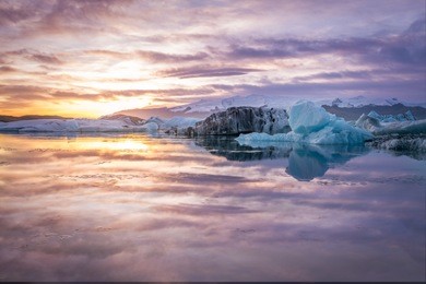 beautiful and colorful sunset over glacier at jokulsarlon, lceland with purple sky and reflection over the water