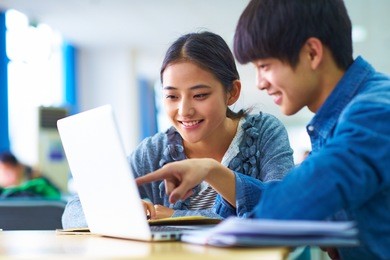 picture of two young chinese college students study together in the library