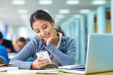 pretty asian college girl using mobile phone in the classroom
