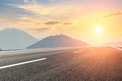 asphalt road and mountains with foggy nature landscape at sunset