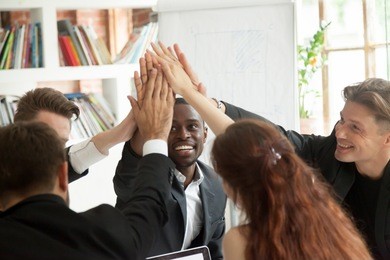 motivated excited multiracial business team giving high five celebrating corporate growth and financial success, diverse group of colleagues join hands together showing unity help support in teamwork