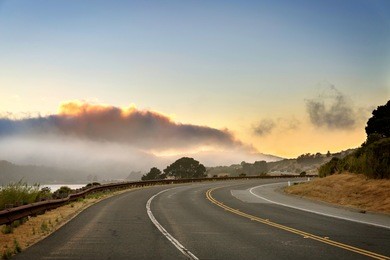 paved road curve to the right, sunset, cloudy sky