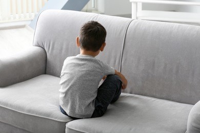 little boy sitting on sofa at home. child autism