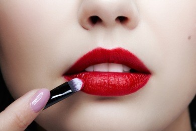 close up portrait of beautiful young woman face. female applying lips makeup with cosmetic brush