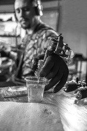 hand of tattoo artist and a tattoo machine.