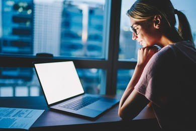 smiling female designer in eyewear satisfied with watching your advertising on blank copy space screen on laptop computer spending evening time at home. woman reading mock up content on modern netbook