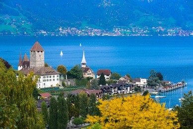 beautiful schloss with port and church at lake thun, autumn leaf, spiez, switzerland