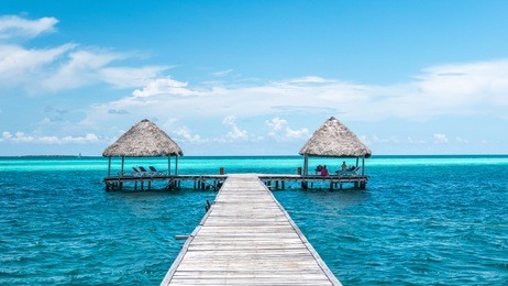 caribbean paradise: the perfect house over the clear water of cuba sea. with palm leaves roof and couple of houses symmetrical built.