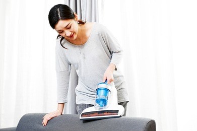 young asian women who do housework clean the mites in the couch using a vacuum cleaner