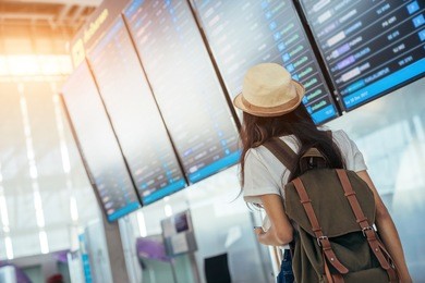 asian teenage girl is using a smartphone to check flight at the international airport to travel on weekends.