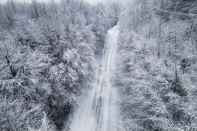 aerial view of snowy forest with a road in the area of naoussa in northern greece.  captured from above with a drone.