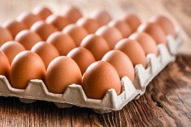chicken eggs in carton box on wooden table. 