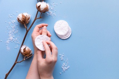 cotton pads for removal makeup with woman hands cotton flowers on the blue background flatlay