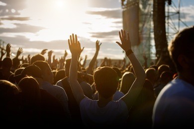 teenagers at summer music festival enjoying themselves, raised hands, sunset