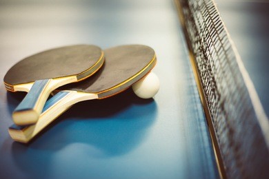 two ping-pong rackets and white balls on the professional table with net