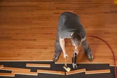 top view of a man installing planks of hardwood floor