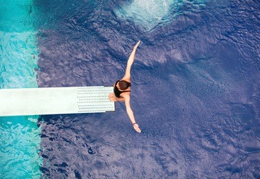 girl standing on springboard, preparing to dive