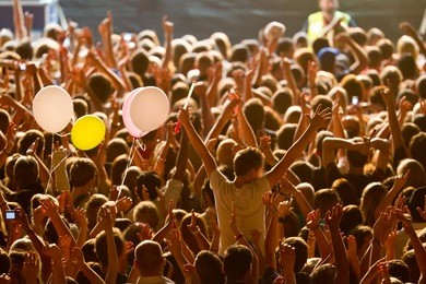 yellow lighted arded crowd at a live concert of a famous rockband