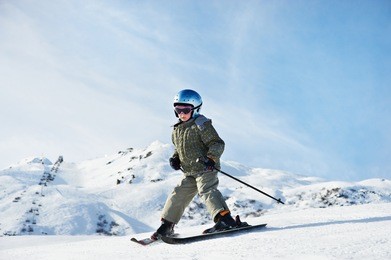small child skiing on snow slope in resort