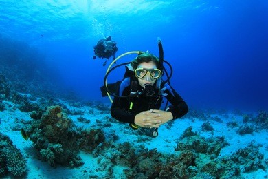young woman scuba diving instructor exploring a coral reef in the red sea