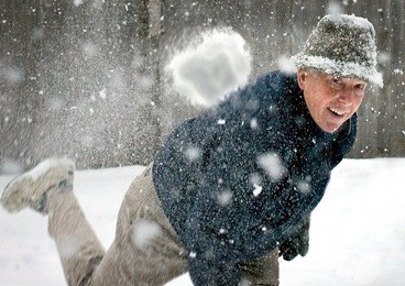 a senior man throwing a snowball