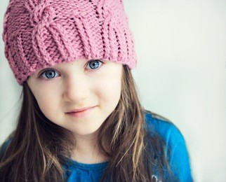 close-up portrait of adorable smiling child girl wearing pink knitted hat