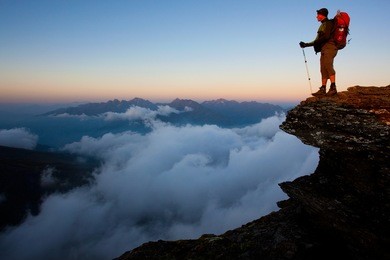man with backpack high above the misty mountain valley