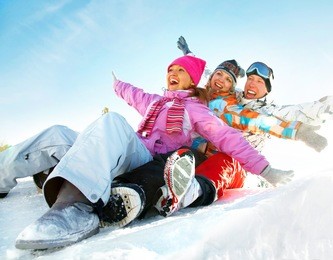 group of  teenagers slide downhill in wintertime