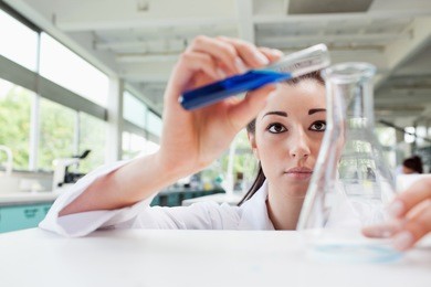 focused science student pouring liquid in an erlenmeyer flask