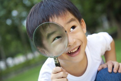 asian boy holding magnifier