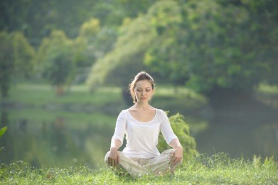 attractive healthy asian woman meditating in the park