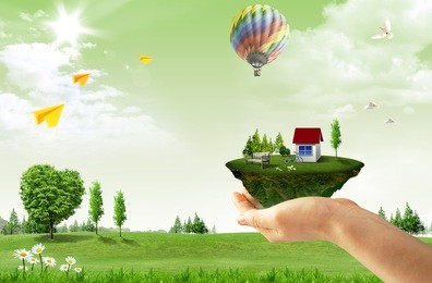 human hand holding houses surrounded by nature