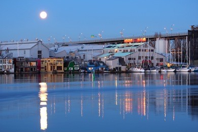 moon rise at dawn over the granville island public market in downtown vancouver, british columbia, canada along the edge of false creek.