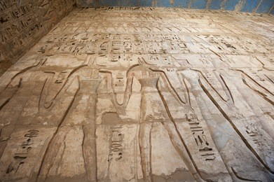 egyptian hieroglyphic carvings on a wall at the temple of medinat habu in luxor