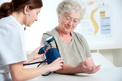 female doctor measuring blood pressure of senior woman