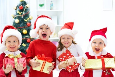 group of four children in christmas hat with presents