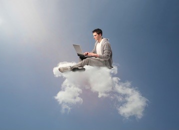 young man sitting on a cloud and using a laptop